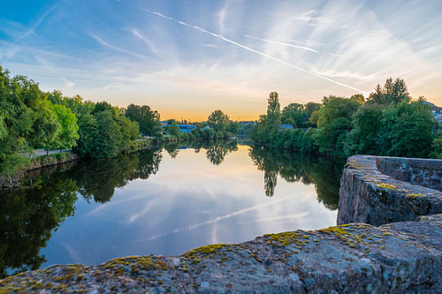 Zonsondergang boven een rustige rivier met bomen die in het water weerspiegeld worden, Frankrijk