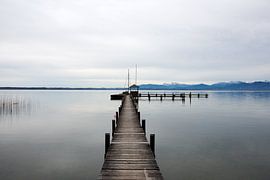 Serene image of a wooden jetty in Lake Chiemsee with a winter mountain landscape in the background. by Robert Lodewijks