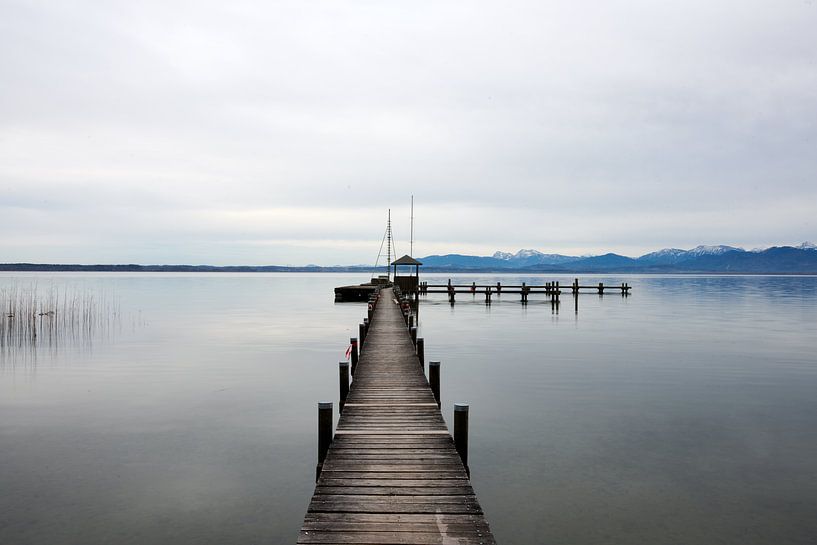 Serene image of a wooden jetty in Lake Chiemsee with a winter mountain landscape in the background. by Robert Lodewijks