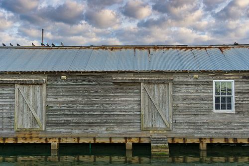 USA, Floride, vieux hangar à bateaux dans le port avec paysage nuageux et eau