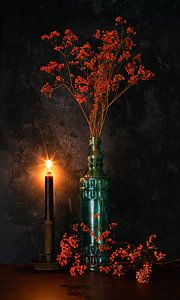 Orange Gypsophila in blauer Flasche und Kerzenlicht.