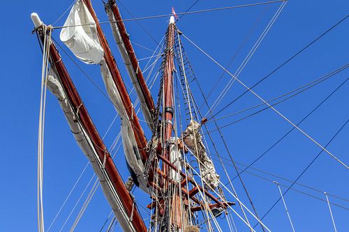 Mât de navigation avec de nombreux cordages devant un ciel bleu