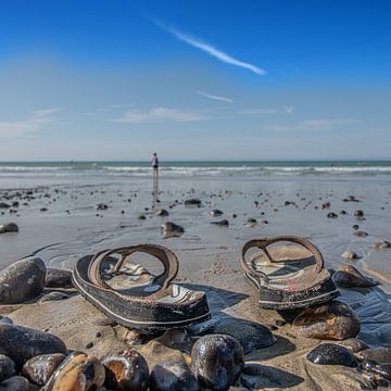 Flip-Flops am Strand, deren Besitzer am Horizont in der Nähe von Meerblick bewegt. von Harrie Muis