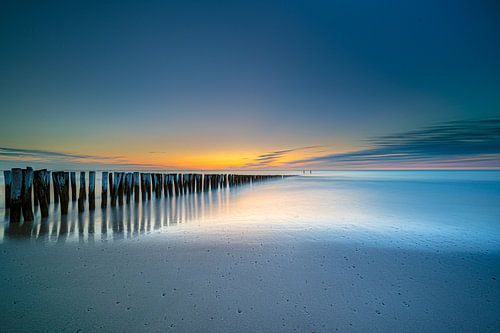 Polköpfe oder Wellenbrecher, die in der Nordsee in Holland verschwinden, mit Sonnenuntergang im Hint