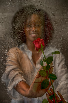 Woman with a red rose behind a window