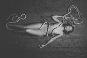 Nackte Frau auf dem Boden liegend in Seil gewickelt