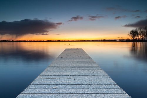 Besneeuwde steiger in het meer van Dirkshorn met aan de horizon een sneeuwbui