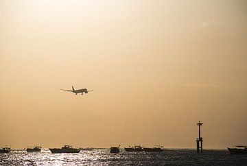 Landend vliegtuig boven zee tijdens zonsondergang van Chantal Schutte