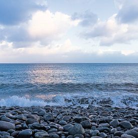 Une plage de galets au bord de l'océan Atlantique à Madère, avec des vagues douces et un ciel aux teintes pastel sur Kristof Lauwers