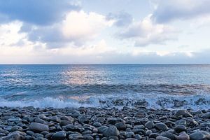 Kiezelstrand langs de Atlantische Oceaan op Madeira met zachte golven en pastel lucht