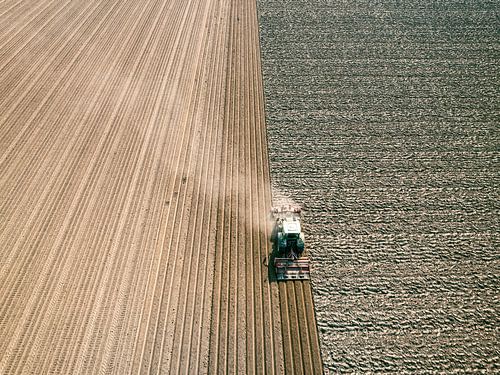 Tractor maakt de grond klaar voor het planten van gewassen van bovenaf gezien