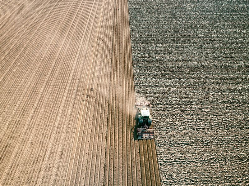 Tractor maakt de grond klaar voor het planten van gewassen van bovenaf gezien van Sjoerd van der Wal Fotografie