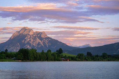 Het Hopfensee-meer tegen de achtergrond van een markante bergtop in het avondlicht