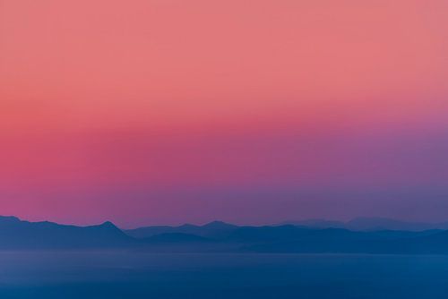 Zonsondergang boven een kalme zee aan de horizon met een lucht met kleurverloop