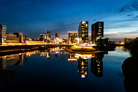 Le Medienhafen de Düsseldorf la nuit, avec ses immeubles de bureaux modernes et son bassin portuaire illuminé sur Your Happy Life