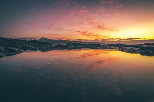 Fuerteventura, Sonnenaufgang an einem Steinstrand mit Spiegelung in einer Pfütze
