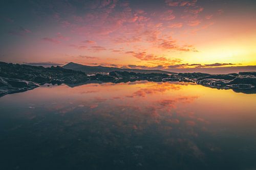 Fuerteventura, zonsopgang op een stenen strand met reflectie in een plasje
