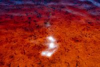 Zonreflecties op oranjerood water