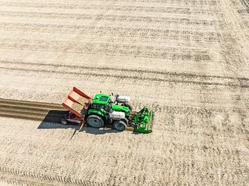 Tractor plant pootaardappels in de grond tijdens de lente van Sjoerd van der Wal