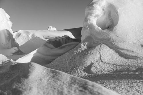 Des dunes de neige sculptées par le vent à l'ombre du coucher de soleil.