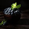 Myrtilles avec feuilles de menthe dans un bol brun sur Iryna Melnyk