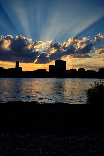 Sunset in Cologne, golden sunbeams, clouds with blue sky city silhouette.