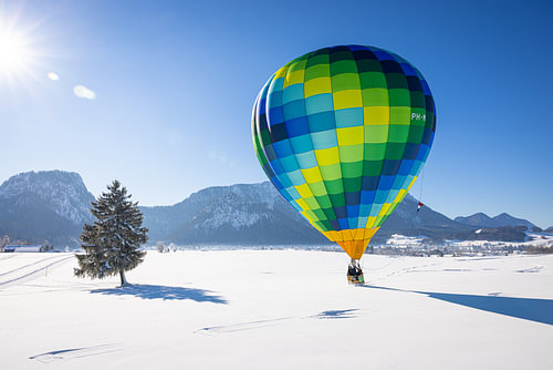 Heteluchtballonnen sieren de lucht boven een besneeuwd Inzell in Duitsland