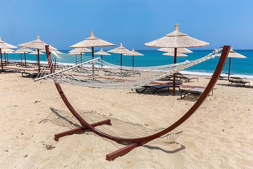 Hangmat met rieten parasols op grieks strand bij zee