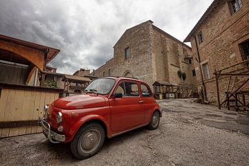 Rode (Fiat 500) auto op plein in Bevagna, Italië van Joost Adriaanse