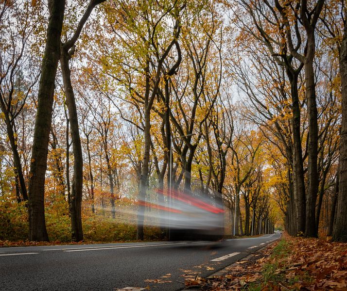 Auto die spookachtig door het herfstlandschap rijdt van Pieter JF Smit