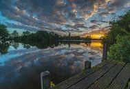 Landschap, zonsopkomst bij steiger met weerspiegeling van wolken in het water van Marcel Kerdijk thumbnail