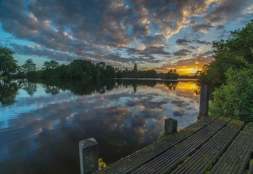 Landschap, zonsopkomst bij steiger met weerspiegeling van wolken in het water