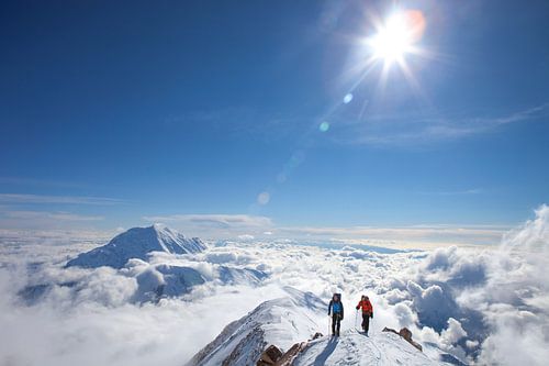 Two alpinists above the clouds on Mount Denali in Alaska