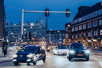 Blauwe uur  in stadstraat, overal branden lichten, het verkeer trekt op, in vintage kleuren van Jan Willem de Groot Photography