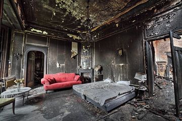 Urbex rode bank in een verbrande hotelkamer. van Dyon Koning