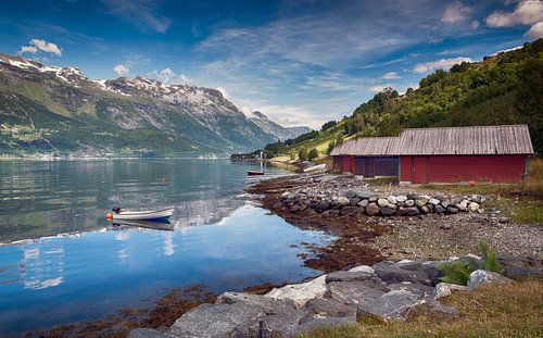 rote häuser und ein boot auf dem fjord in norwegen