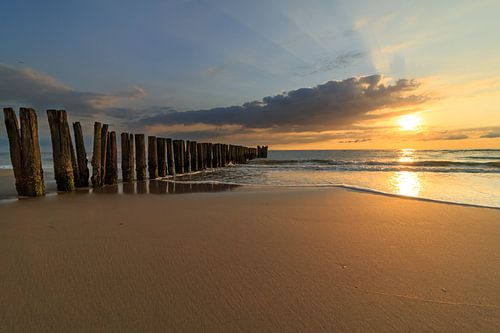 sunset over beach with row of poles