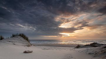 Zicht op de Noordzee met ondergaande zon en dreigende wolkenlucht vanaf de duinen van de Nederlandse kust van Bram Lubbers