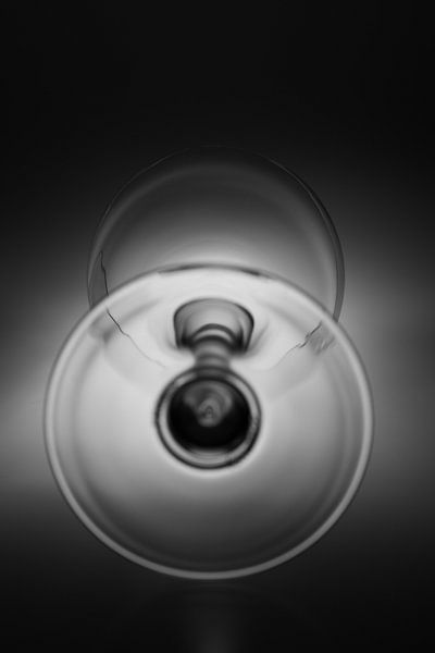 Zwart wit afbeelding van een wijn glas met een zochte achtergrond belichting van Kim Willems