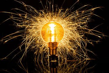 Een gloeilamp die explodeert in een zee van gouden vonken, symbool voor inspiratie, creativiteit en energie. van Peter van Dam