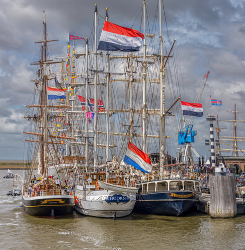 Des drapeaux néerlandais flottent au-dessus des grands voiliers dans le port de Harlingen sur John Kreukniet