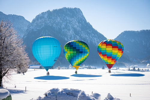Heteluchtballonnen sieren de lucht boven een besneeuwd Inzell in Duitsland