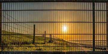 Zonsondergang achter een hek op de dijk nij PaesensModdergat van Harrie Muis