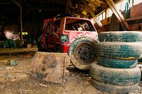Abandoned Workshop with Old Red Car and Stack of Tyres