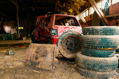 Verlaten Werkplaats met Oude Rode Auto en Stapel Banden