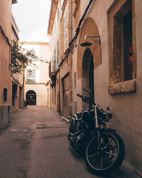 Motor in de traditionele straatjes van het historische Spaanse dorpje Pollença op Mallorca van Michiel Dros
