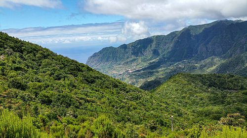 Mountain slope with lush green vegetation before mountain and sky with clouds