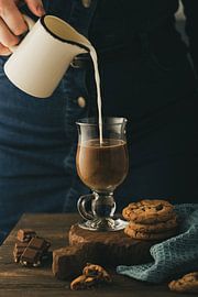 Woman pouring milk in glass with coffee by Iryna Melnyk