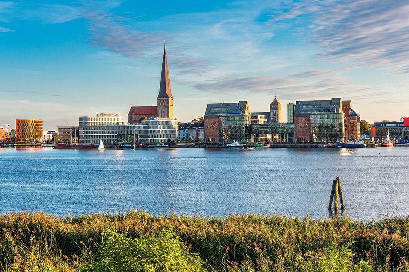 Uitzicht over de Warnow naar de Hanzestad Rostock bij avond van Rico Ködder