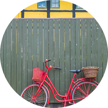 Rode fiets staat voor een groene schutting in Ribe Denemarken van Marc Venema